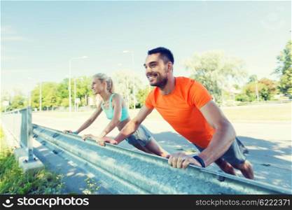 fitness, sport, training and healthy lifestyle concept - close up of happy couple doing push-ups outdoors