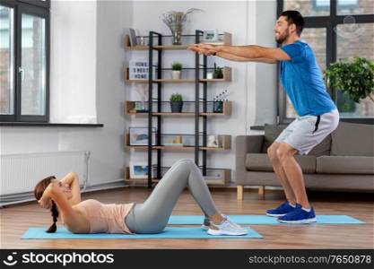fitness, sport, training and healthy lifestyle concept - happy young man and woman exercising at home. happy young man and woman exercising at home