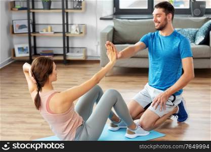 fitness, sport, training and healthy lifestyle concept - woman with personal trainer doing sit ups at home. woman with personal trainer doing sit ups at home