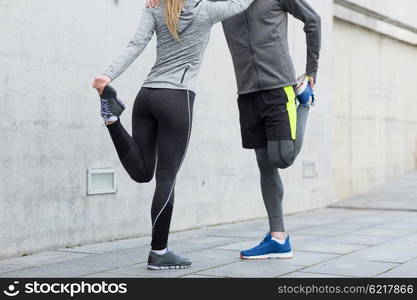 fitness, sport, training and lifestyle concept - close up of couple stretching legs outdoors