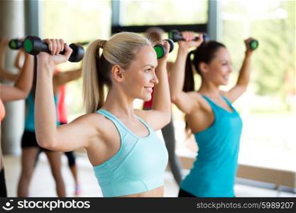 fitness, sport, training and lifestyle concept - group of women with dumbbells in gym