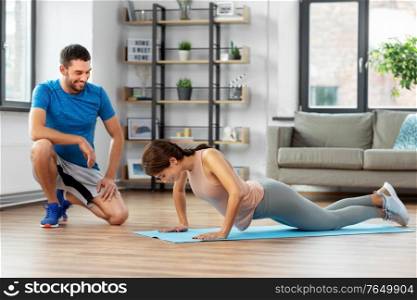 fitness, sport, training and lifestyle concept - happy smiling woman with personal trainer doing push-ups at home. woman with personal trainer doing push-ups at home