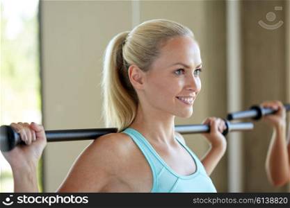 fitness, sport, training and lifestyle concept - happy woman exercising with bar in gym