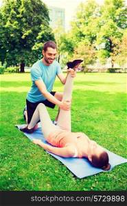 fitness, sport, training and lifestyle concept - smiling couple stretching on mat outdoors