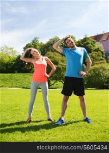 fitness, sport, training and lifestyle concept - smiling couple stretching outdoors