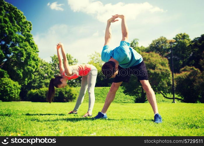 fitness, sport, training and lifestyle concept - smiling couple stretching outdoors