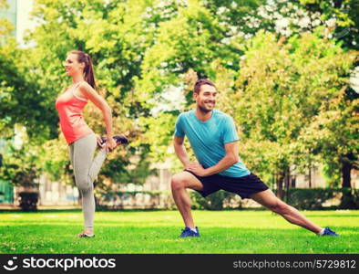 fitness, sport, training and lifestyle concept - smiling couple stretching outdoors