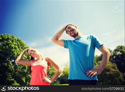 fitness, sport, training and lifestyle concept - smiling couple stretching outdoors