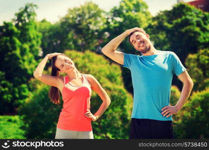 fitness, sport, training and lifestyle concept - smiling couple stretching outdoors