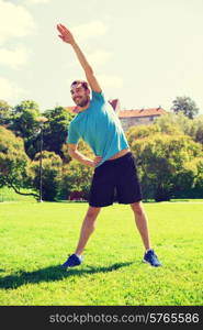 fitness, sport, training and lifestyle concept - smiling man stretching hand outdoors