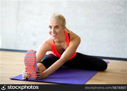 fitness, sport, training and lifestyle concept - smiling woman doing exercises on mat in gym