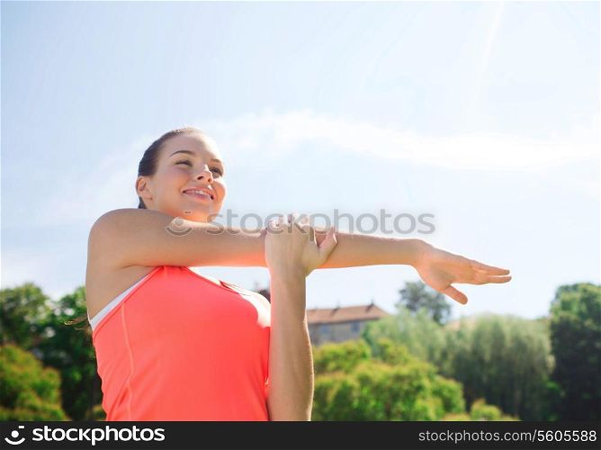 fitness, sport, training and lifestyle concept - smiling woman stretching hand outdoors