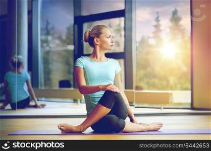 fitness, sport, training and lifestyle concept - smiling woman stretching leg on mat in gym. smiling woman stretching leg on mat in gym