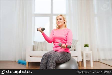 fitness, sport, training and lifestyle concept - smiling woman with dumbbells and fit ball exercising at home