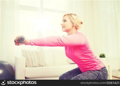 fitness, sport, training and lifestyle concept - smiling woman with dumbbells exercising and doing squats at home. smiling woman with dumbbells exercising at home