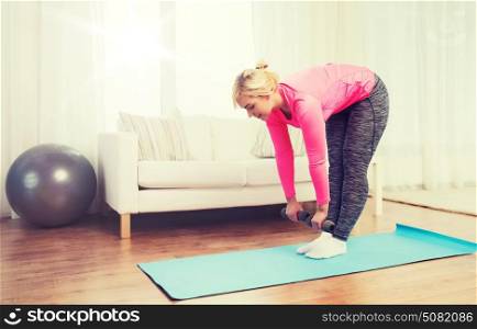 fitness, sport, training and lifestyle concept - smiling woman with dumbbells exercising and doing lean at home. smiling woman with dumbbells exercising at home