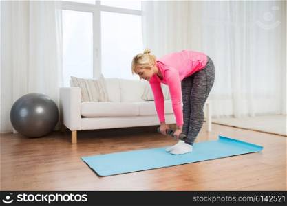fitness, sport, training and lifestyle concept - smiling woman with dumbbells exercising and doing lean at home