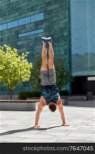fitness, sport, training and lifestyle concept - young man exercising and doing handstand outdoors. young man exercising and doing handstand outdoors