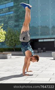 fitness, sport, training and lifestyle concept - young man exercising and doing handstand outdoors. young man exercising and doing handstand outdoors