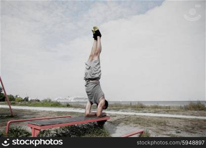 fitness, sport, training and lifestyle concept - young man exercising on bench outdoors
