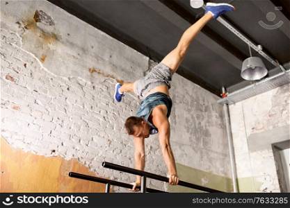 fitness, sport, training and lifestyle concept - young man exercising on parallel bars in gym. young man exercising on parallel bars in gym