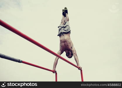 fitness, sport, training and lifestyle concept - young man exercising on parallel bars outdoors