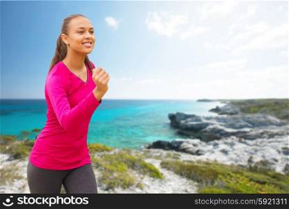 fitness, sport, training and people concept - smiling african american woman running outdoors over beach background
