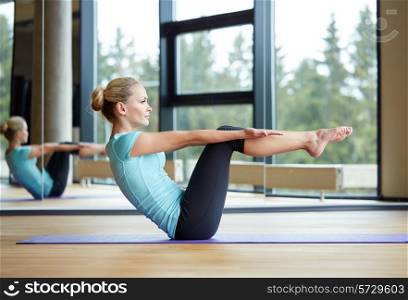 fitness, sport, training and people concept - smiling woman doing abdominal exercises on mat in gym