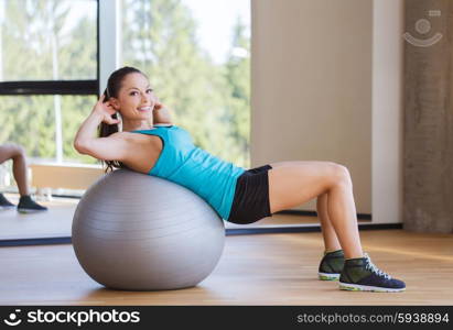 fitness, sport, training and people concept - smiling woman flexing abdominal muscles with exercise ball in gym