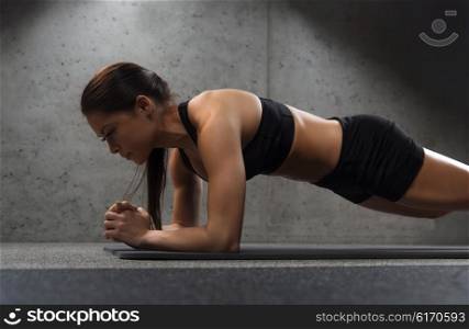 fitness, sport, training and people concept - woman doing plank exercise on mat in gym