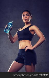 fitness, sport, training, drink and lifestyle concept - woman drinking water from bottle in gym. woman drinking water from bottle in gym