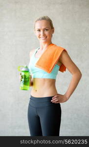 fitness, sport, training, drink and lifestyle concept - woman with bottle of water in gym