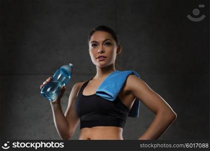 fitness, sport, training, drink and lifestyle concept - woman with towel drinking water from bottle in gym