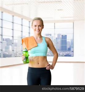 fitness, sport, training, drink and people concept - happy woman with bottle of water and towel over gym or home background