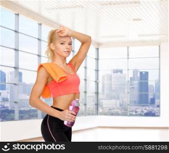 fitness, sport, training, drink and people concept - happy woman with bottle of water and towel over gym or home background