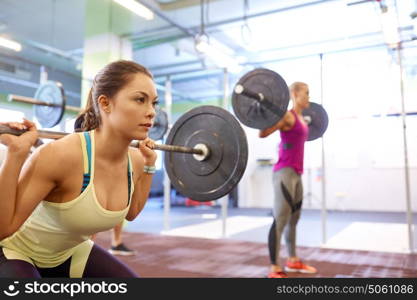 fitness, sport, training, exercising and lifestyle concept - group of people with barbells doing squats in gym. group of people training with barbells in gym