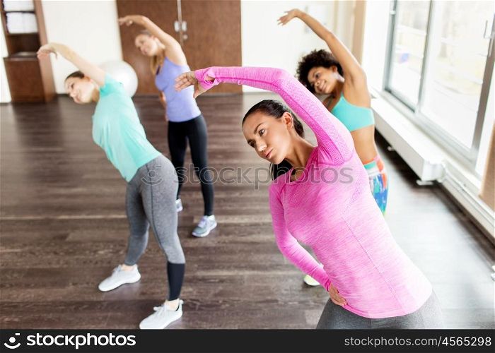 fitness, sport, training, exercising and people concept - group of happy women working out and stretching in gym