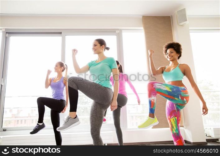 fitness, sport, training, exercising and people concept - group of happy women working out and raising legs leg in gym