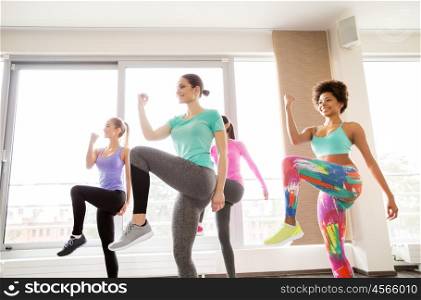 fitness, sport, training, exercising and people concept - group of happy women working out and raising legs leg in gym