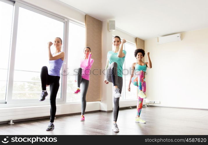 fitness, sport, training, exercising and people concept - group of happy women working out and raising legs leg in gym