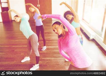 fitness, sport, training, exercising and people concept - group of happy women working out and stretching in gym