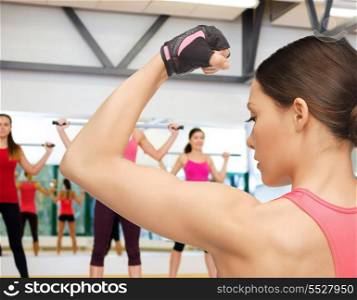 fitness, sport, training, gym and lifestyle concept - beautiful sporty woman flexing her biceps in gym