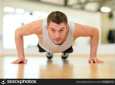 fitness, sport, training, gym and lifestyle concept - concentrated man doing push-ups in the gym