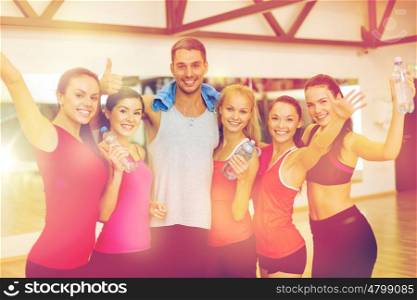 fitness, sport, training, gym and lifestyle concept - group of happy people in the gym with water bottles and towel showing thumbs up and waving hands