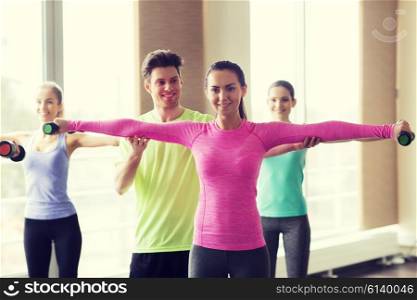 fitness, sport, training, gym and lifestyle concept - group of happy women and trainer with dumbbells flexing muscles in gym