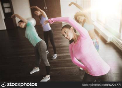 fitness, sport, training, gym and lifestyle concept - group of happy women working out and stretching in gym