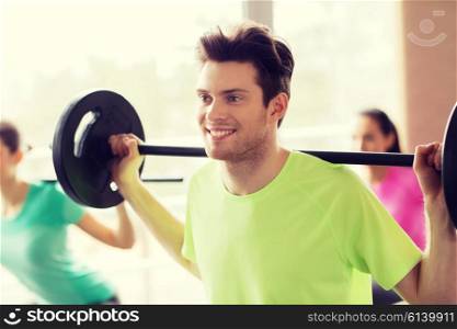 fitness, sport, training, gym and lifestyle concept - group of people exercising with barbell in gym