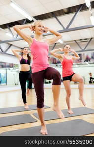 fitness, sport, training, gym and lifestyle concept - group of smiling female with trainer exercising in the gym