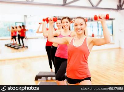 fitness, sport, training, gym and lifestyle concept - group of smiling female with dumbbells and aerobic step