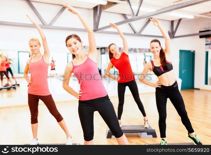 fitness, sport, training, gym and lifestyle concept - group of smiling female doing stretching in gym